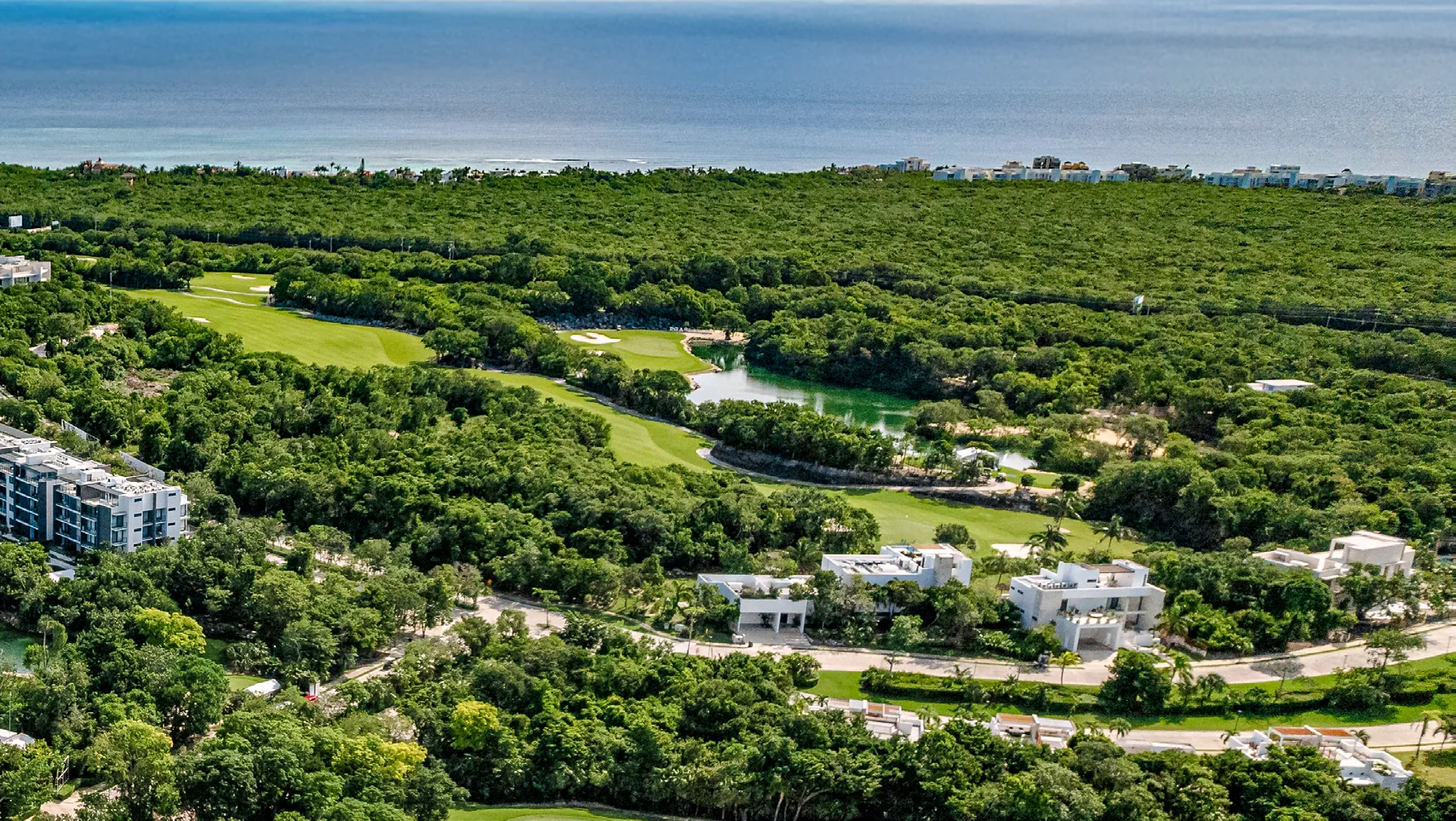 Aerial view of Tulum Country Club, its golf landscape, cenote and Caribbean coast